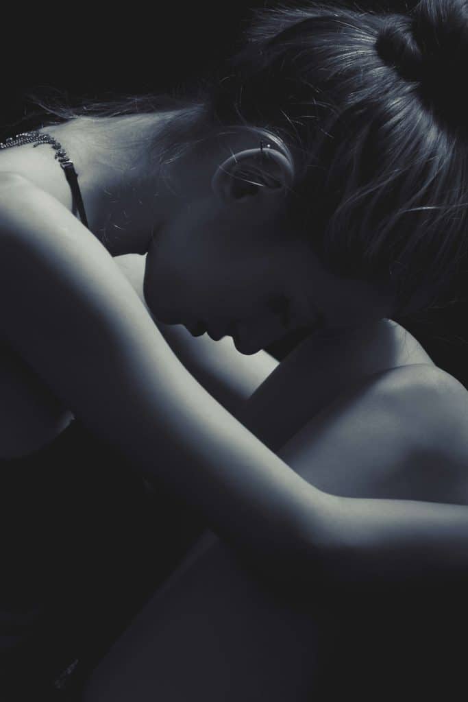 Woman bent over with head resting on knees